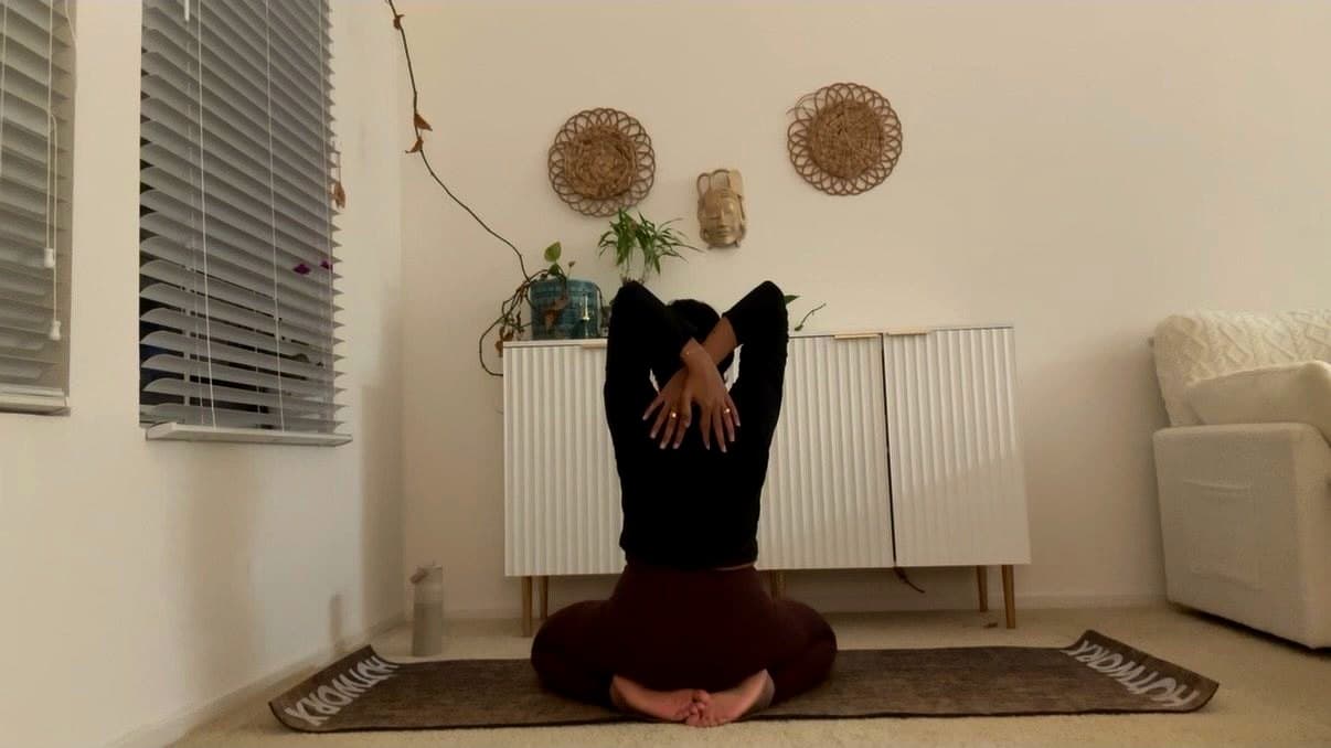 Seated bound-angle fold with eagle arms during home practice.