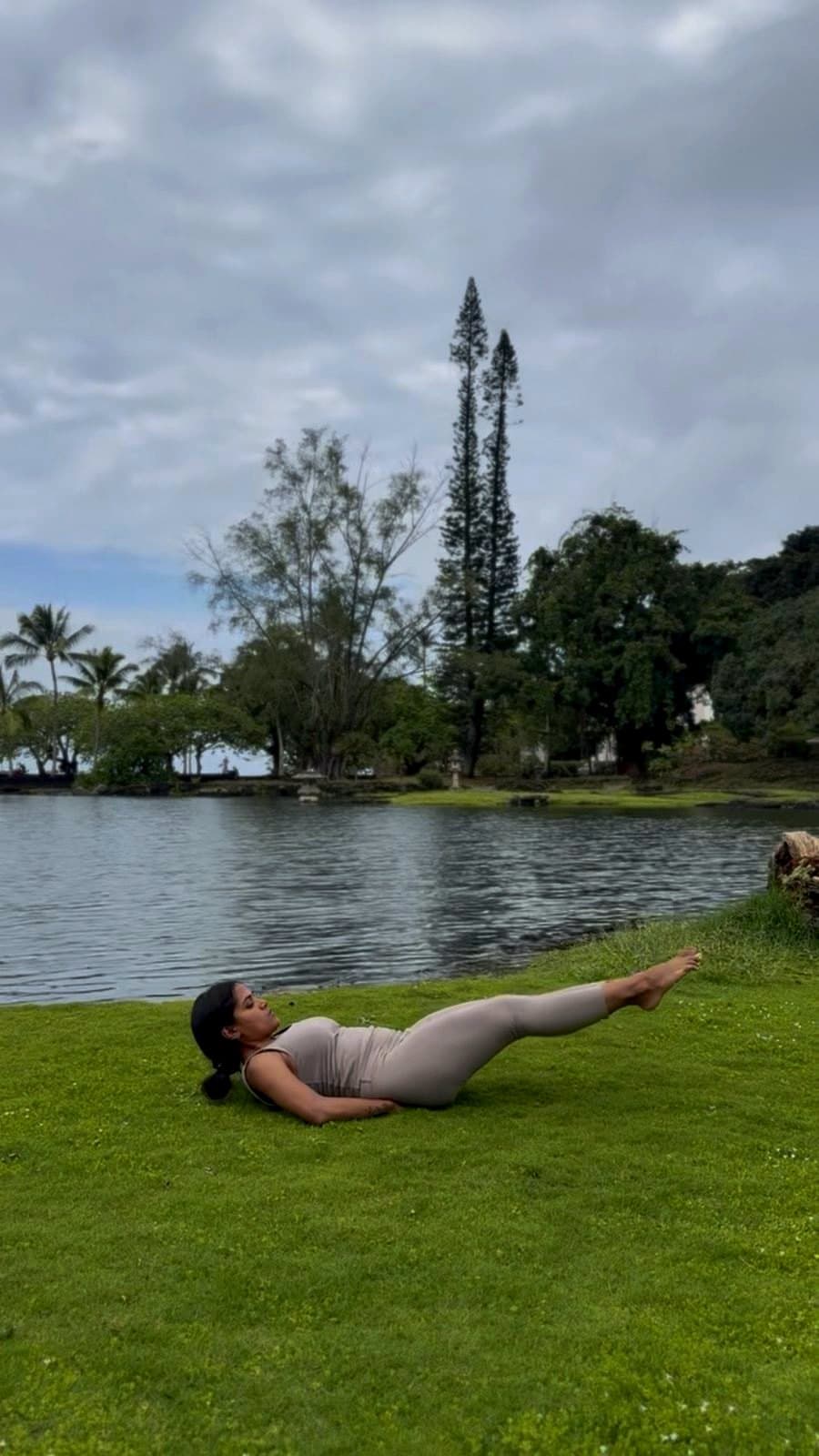 Low boat pose on a lakeside lawn.